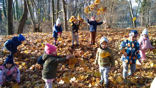 Dzieci bawią się jesiennymi liściami