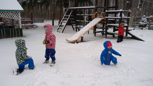 Dzieci bawią się w śniegu na przedszkolnym podwórku